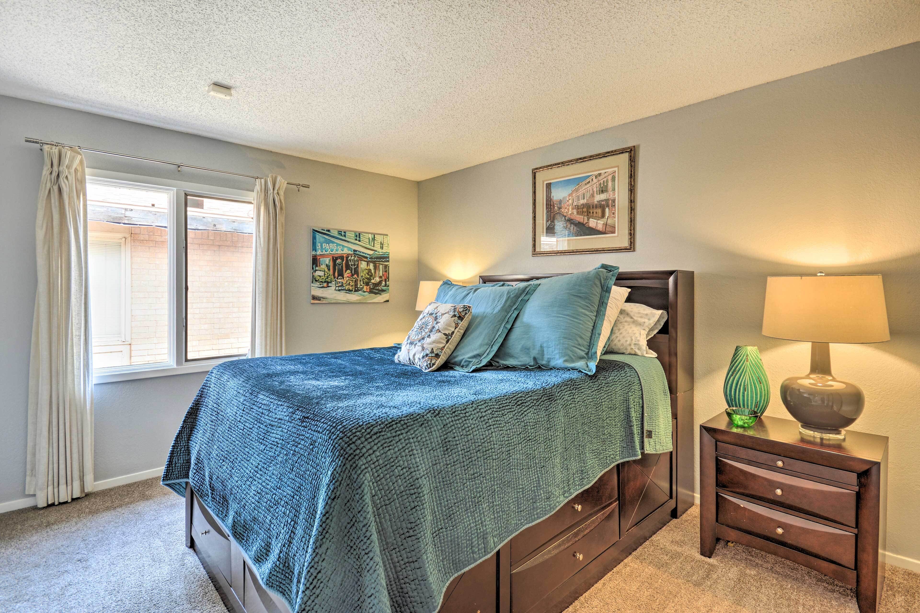 A bedroom with a bed, a nightstand, a lamp, and a window with curtains.