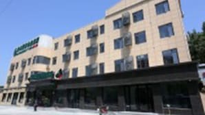 Een hotel met meerdere verdiepingen, een plat gevelontwerp, veel ramen en een bord dat het gebouw als hotel identificeert.