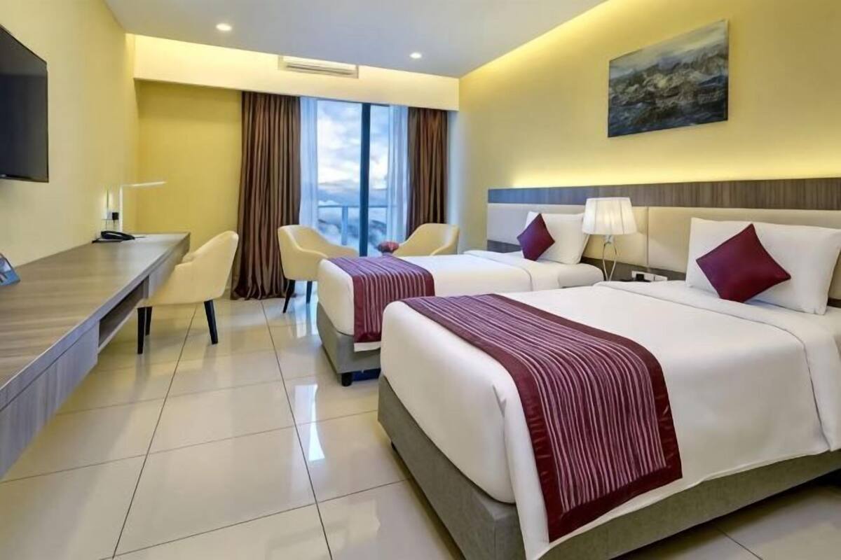 Une chambre d’hôtel avec deux lits, un bureau, une chaise et une vue sur la ville.