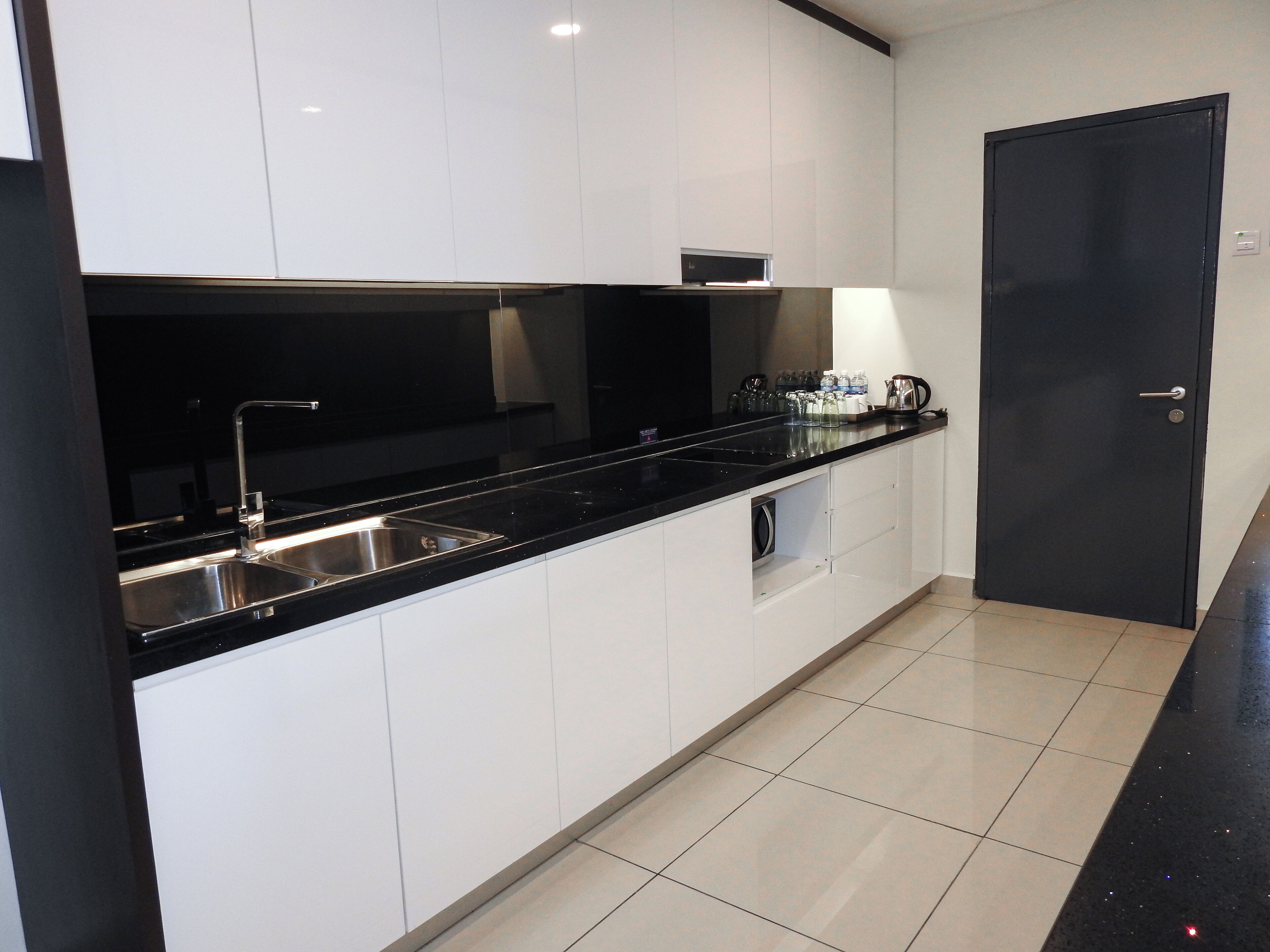 A modern kitchen with black countertops, stainless steel sinks, and white cabinets.