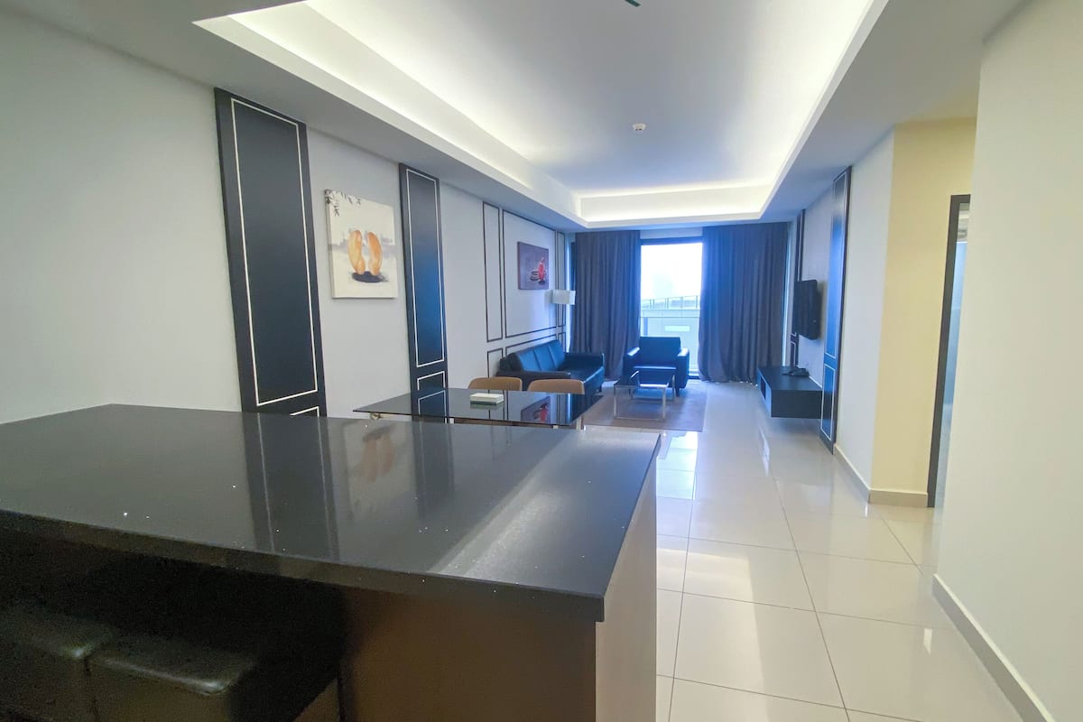 Une chambre d’hôtel moderne dotée d’une grande cuisine, d’un coin salon avec un canapé et des fauteuils, et offrant une vue sur la ville.
