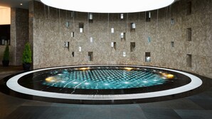 Une piscine intérieure moderne, de forme circulaire, entourée d’une bordure carrelée en noir et blanc.