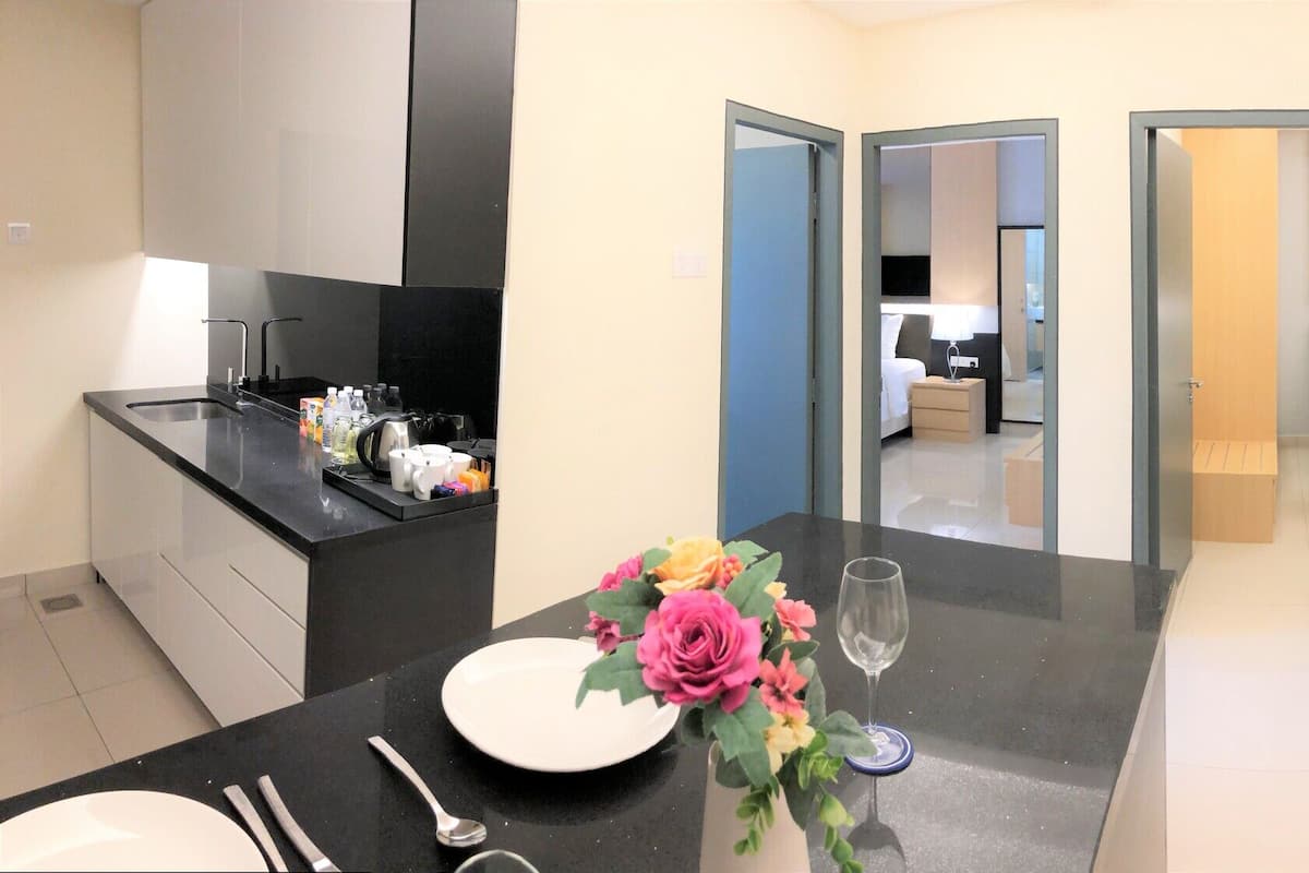 Une chambre d’hôtel moderne dotée d’une cuisine, d’un espace de vie avec un canapé et une table basse, et d’une porte donnant accès à une salle de bain.