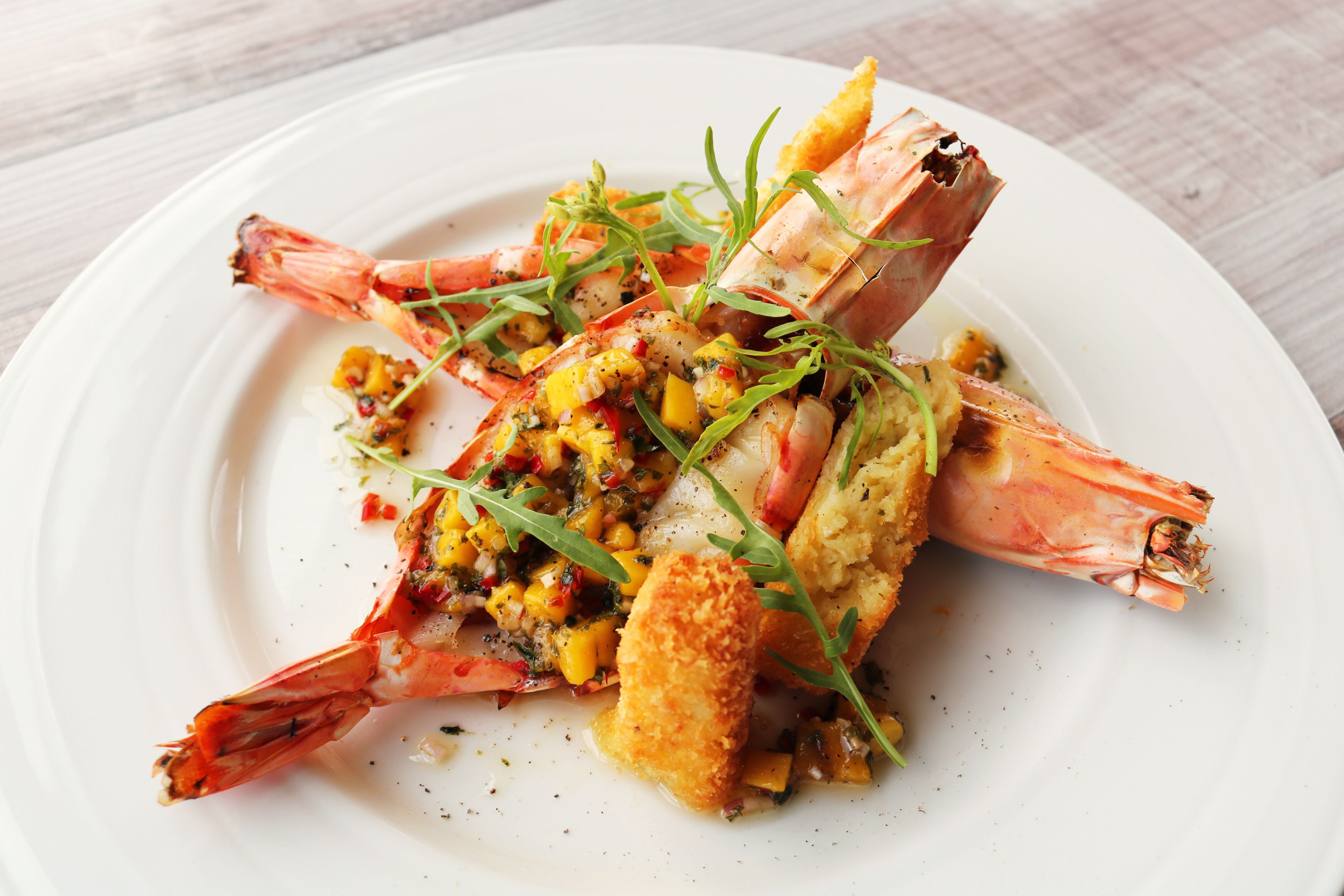 A plate of food with grilled shrimp, corn, and greens.