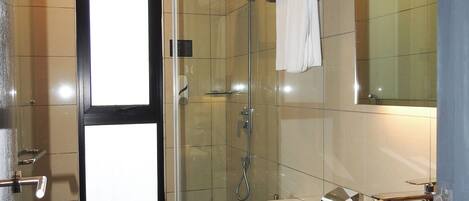 Un baño moderno con ducha envuelta en vidrio, inodoro, lavamanos y espejo.