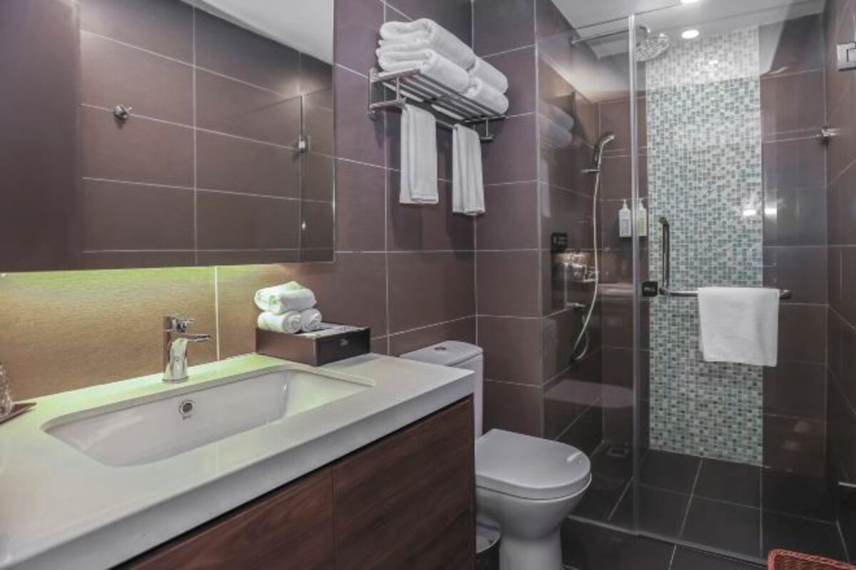 Een moderne badkamer met een groot wastafel, toilet en een douche met glazen wand.