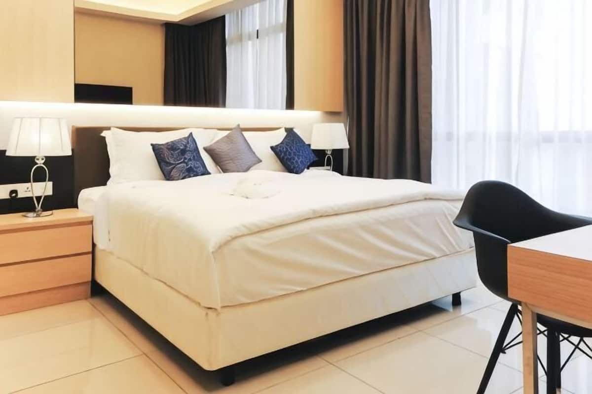 Une chambre d’hôtel avec un lit, des tables de chevet, un bureau et une chaise.