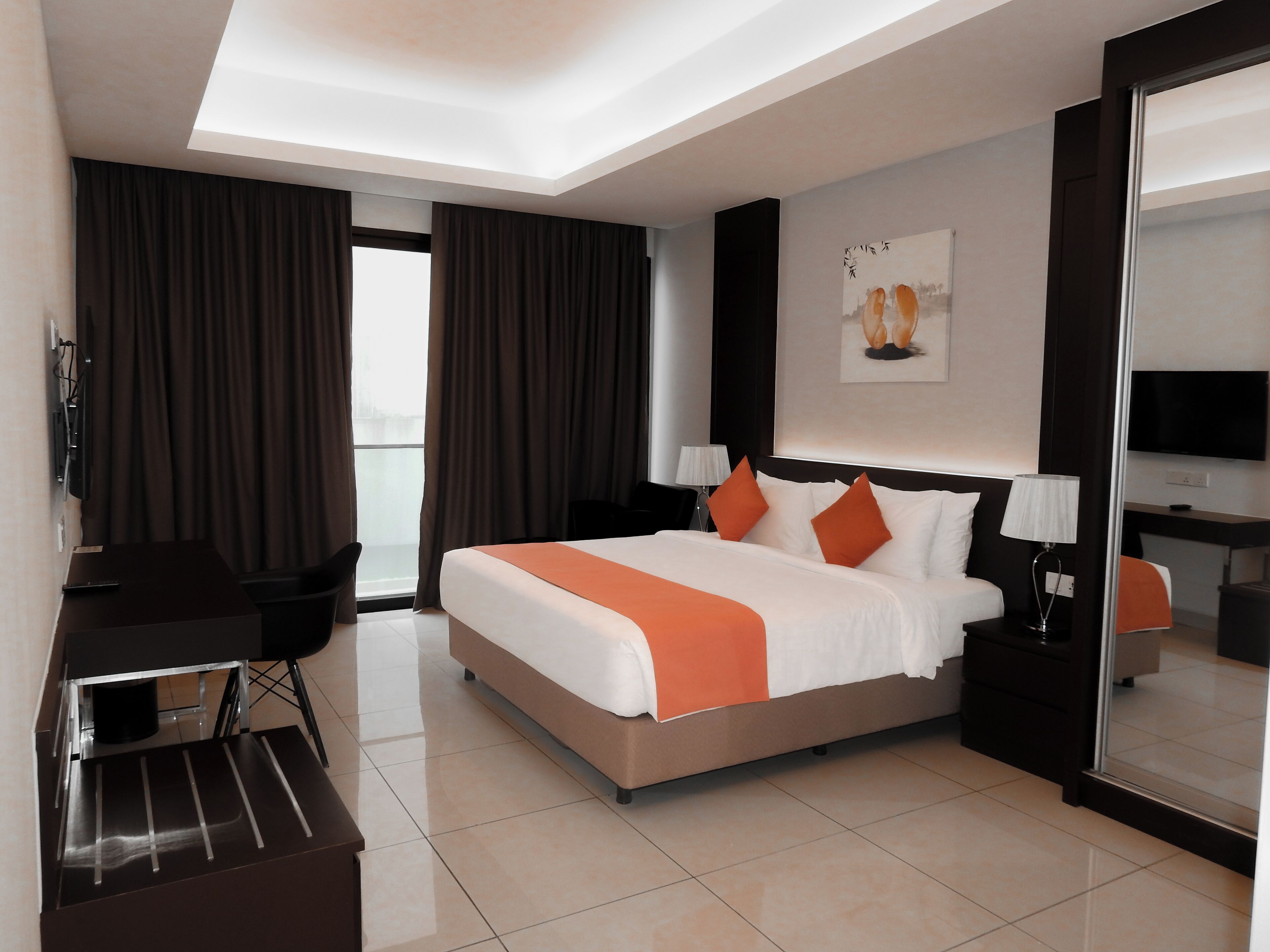Una habitación de hotel moderna con una cama grande, un escritorio, una silla y un televisor.