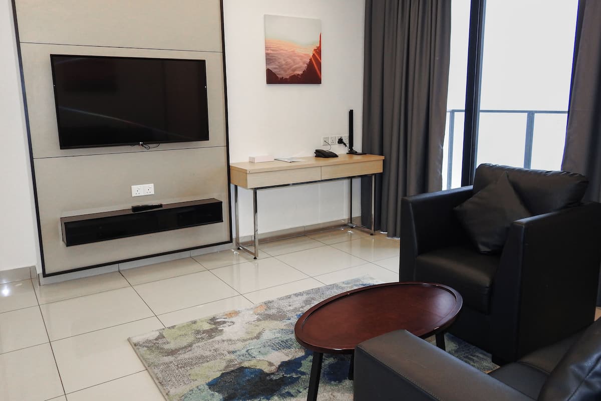Un salon moderne avec un téléviseur à écran plat, un petit bureau, un canapé et une table basse.
