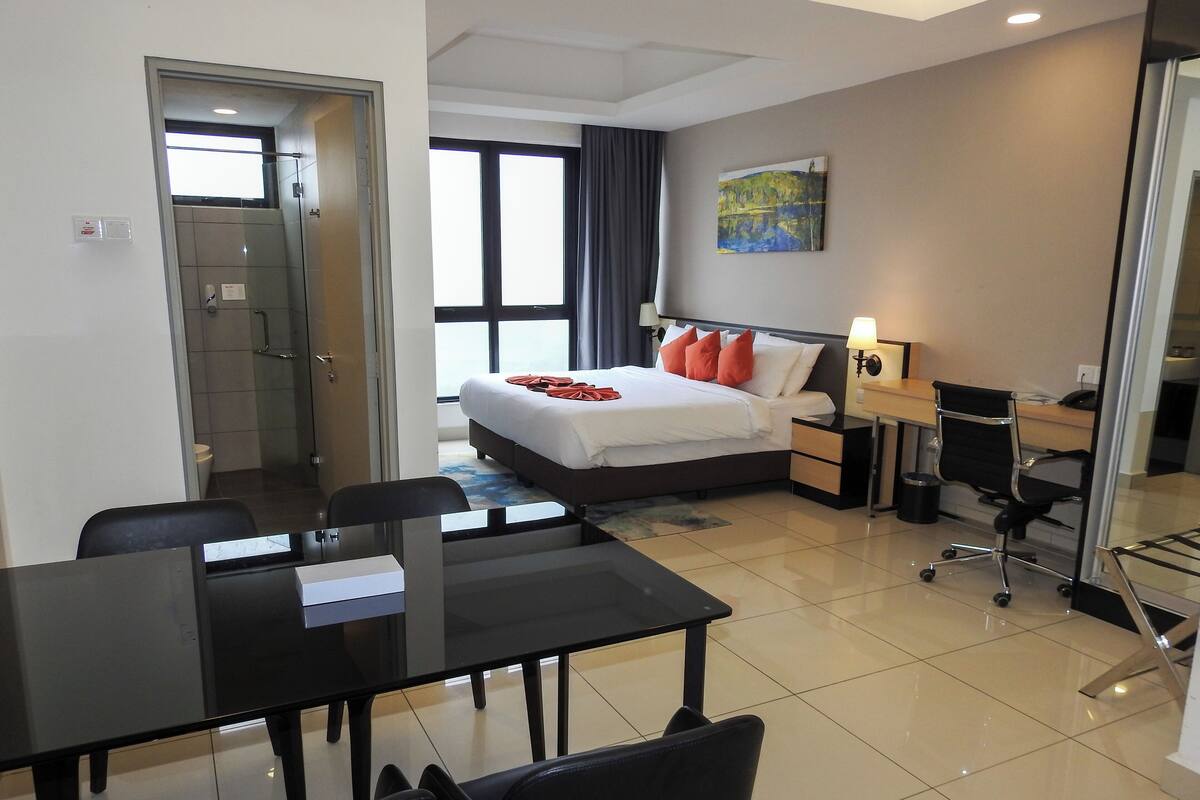Une chambre d’hôtel avec un lit, un bureau, une chaise et une petite table.