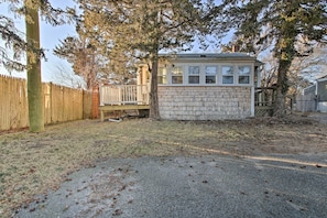 A small wooden cabin with a deck, surrounded by a wooden fence and trees. - Steps to Cape Cod Canal: Pet-Friendly Home (Buzzards Bay)