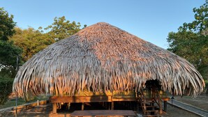 A thatched-roof hut with a wooden bench in front. - Yala Lake View Cabanas (Thissamaharama)
