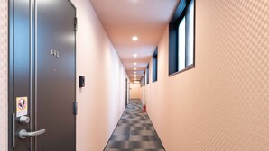 A hallway with a checkered carpet, a door labeled "102", and a fire extinguisher on the right. - Hotel MUSUBI KYOTO Saiin (Kyoto)