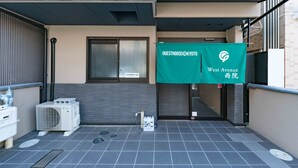 A hotel entrance with a green banner, air conditioning units, and a tiled floor. - Hotel MUSUBI KYOTO Saiin (Kyoto)
