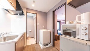 A compact kitchen with a sink, a built-in oven, and a microwave. - Hotel MUSUBI KYOTO Saiin (Kyoto)