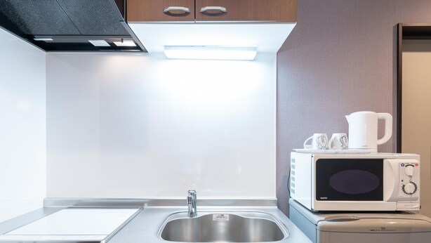A modern kitchen with a stainless steel sink, a microwave, and a coffee maker. - Hotel MUSUBI KYOTO Saiin (Kyoto)