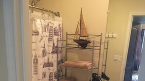 A bathroom with a toilet, a sink, a mirror, and a shelf with towels.