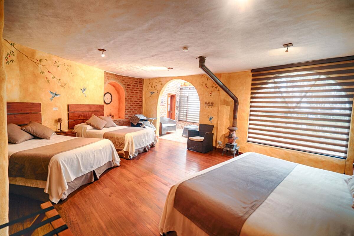 Une chambre d’hôtel avec deux lits, un plancher en bois, un mur en briques et une grande fenêtre avec des stores.