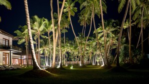 A nighttime view of a resort with palm trees and a well-lit pool area. - The Villa by Contemporary Ceylon (Wadduwa)