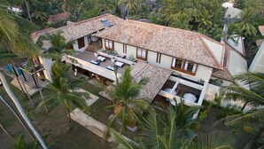 A two-story house with a tiled roof, surrounded by palm trees. - The Villa by Contemporary Ceylon (Wadduwa)