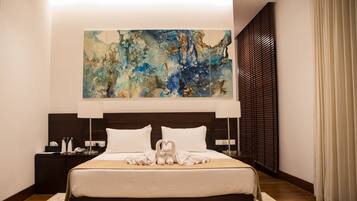 A modern hotel room with a large abstract painting above the bed, a neatly made bed with white linens, and a dark wood headboard.
