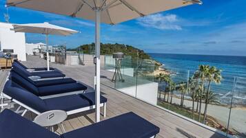 A deck with sun loungers and umbrellas overlooking a beach.