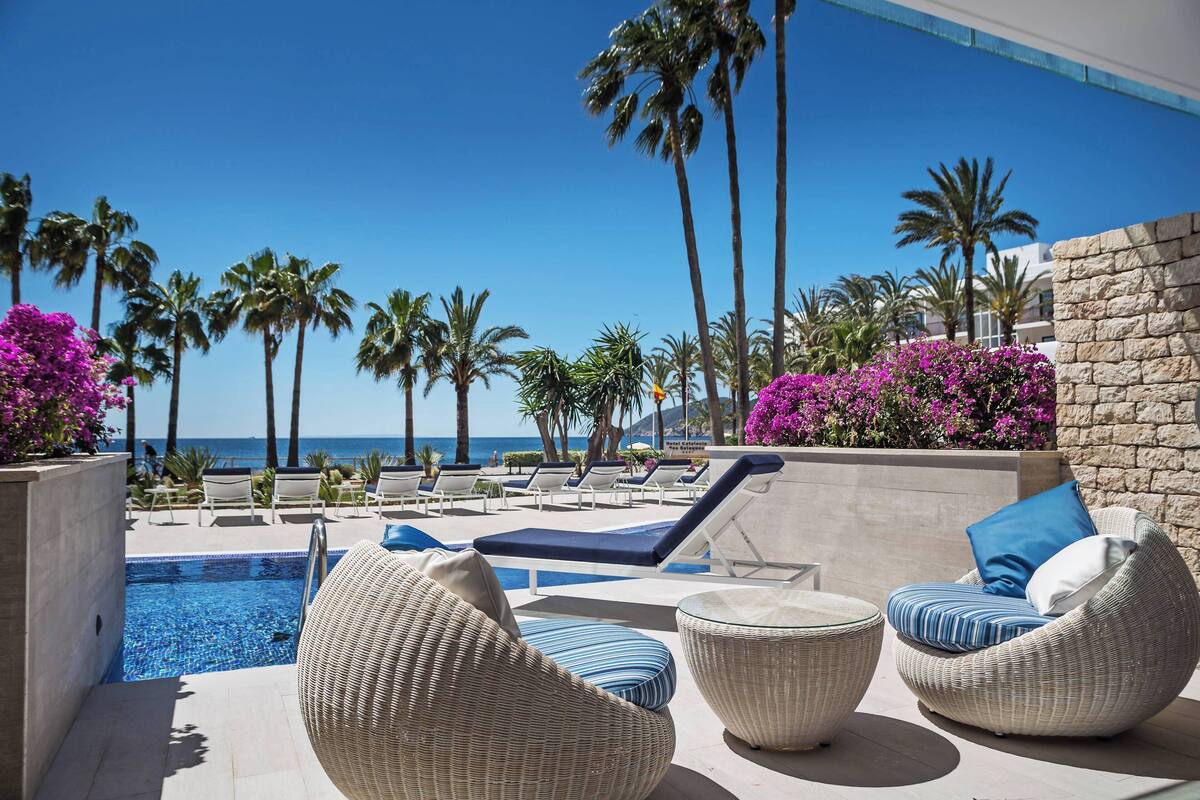A poolside area with lounge chairs and a view of the ocean.