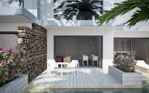A modern outdoor pool area with stone walls, white furniture, and tropical plants. - Catalonia Royal Ses Estaques (Santa Eulalia del Rio)