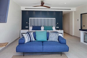 Un dormitorio moderno con una cama, un sofá azul, un ventilador de techo y una mesita de noche con una lámpara.