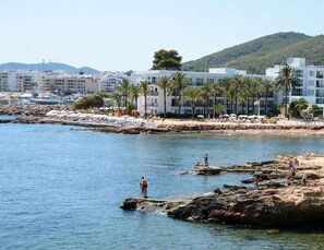 A coastal hotel with a rocky shoreline, palm trees, and a view of the sea. - Catalonia Royal Ses Estaques (Santa Eulalia del Rio)
