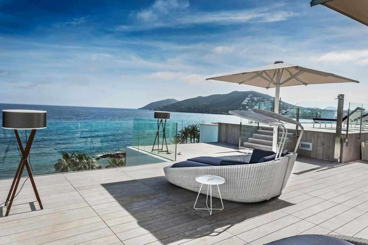 Een modern zitgedeelte buiten met uitzicht op zee, een grote parasol en een kleine tafel.
