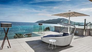 Een modern zitgedeelte buiten met uitzicht op zee, een grote parasol en een kleine tafel.