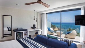 Une chambre d’hôtel moderne dotée d’un grand lit, d’un bureau, d’une télévision à écran plat et offrant une vue sur l’océan.