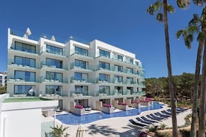 A modern hotel with multiple balconies, a swimming pool, and palm trees. - Catalonia Royal Ses Estaques (Santa Eulalia del Rio)