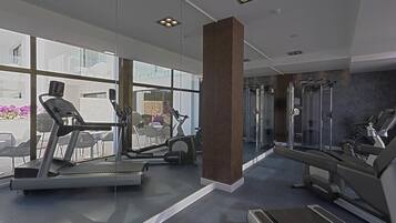 Une salle de sport moderne équipée de tapis de course, de vélos elliptiques et de matériel de musculation.