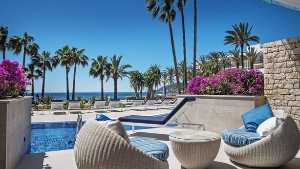 Un espace aménagé au bord de la piscine, avec des chaises longues et une vue sur l’océan.