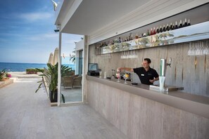 A modern bar area with a view of the ocean, a bartender, and a well-stocked bar. - Catalonia Royal Ses Estaques (Santa Eulalia del Rio)