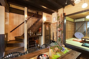 Ein traditionelles japanisches Interieur mit einer Holztreppe, Tatami-Bodenbelag und einem Essbereich mit gedecktem Tisch.