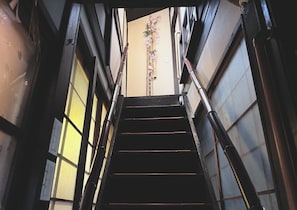 Un escalier muni d’une rampe, menant à une porte ornée de motifs floraux.