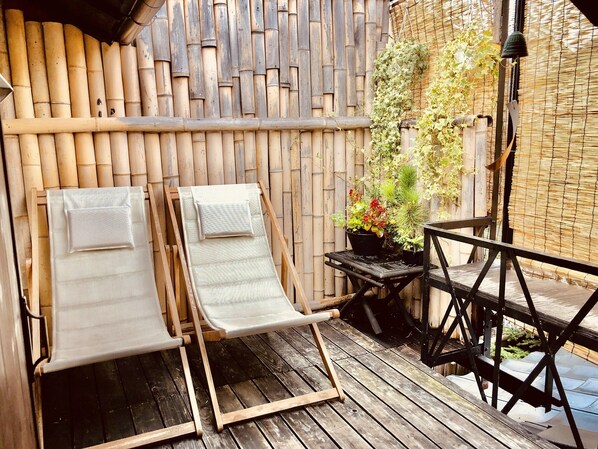 A wooden deck with two lounge chairs and a small table.