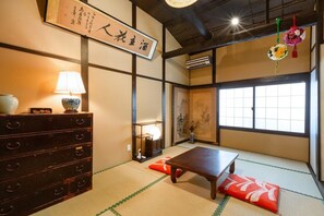 Ein traditioneller japanischer Raum mit Tatami-Bodenbelag, einem niedrigen Holztisch, einem Schmuckkästchen und einem Shoji-Bildschirm.