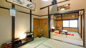 A traditional Japanese room with tatami flooring, a shoji screen, and a low table.