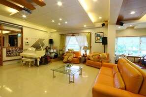 A well-lit living room with a piano, sofas, and a glass coffee table.