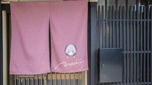 A pink cloth with a logo and text hanging on a metal gate. - Kyo Cottage Machico Mibu (Kyoto)