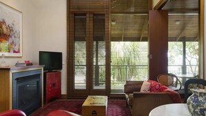 Una sala de estar con televisor, un mueble rojo, una mesa de madera y un sofá.