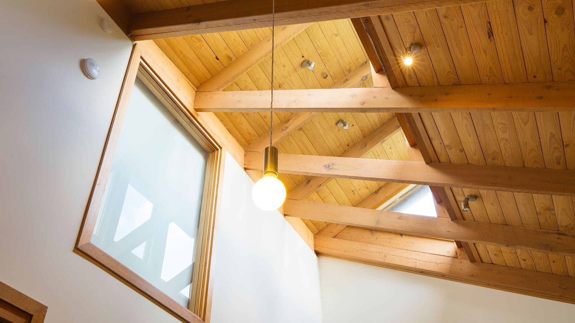 A high ceiling with wooden beams and a skylight.