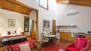 Una habitación acogedora con una cama, un sofá rojo, una mesa de comedor y una cocina.