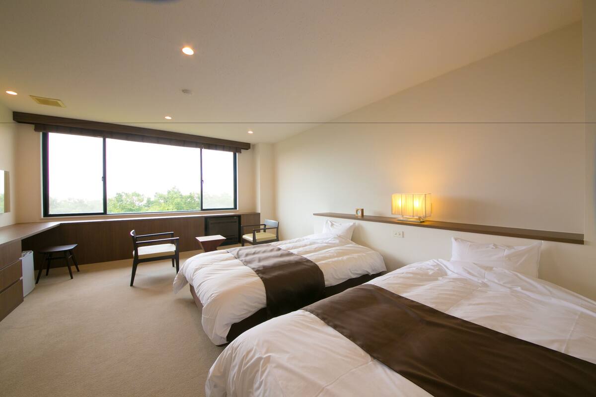 Une chambre d’hôtel avec deux lits, un bureau et une chaise.