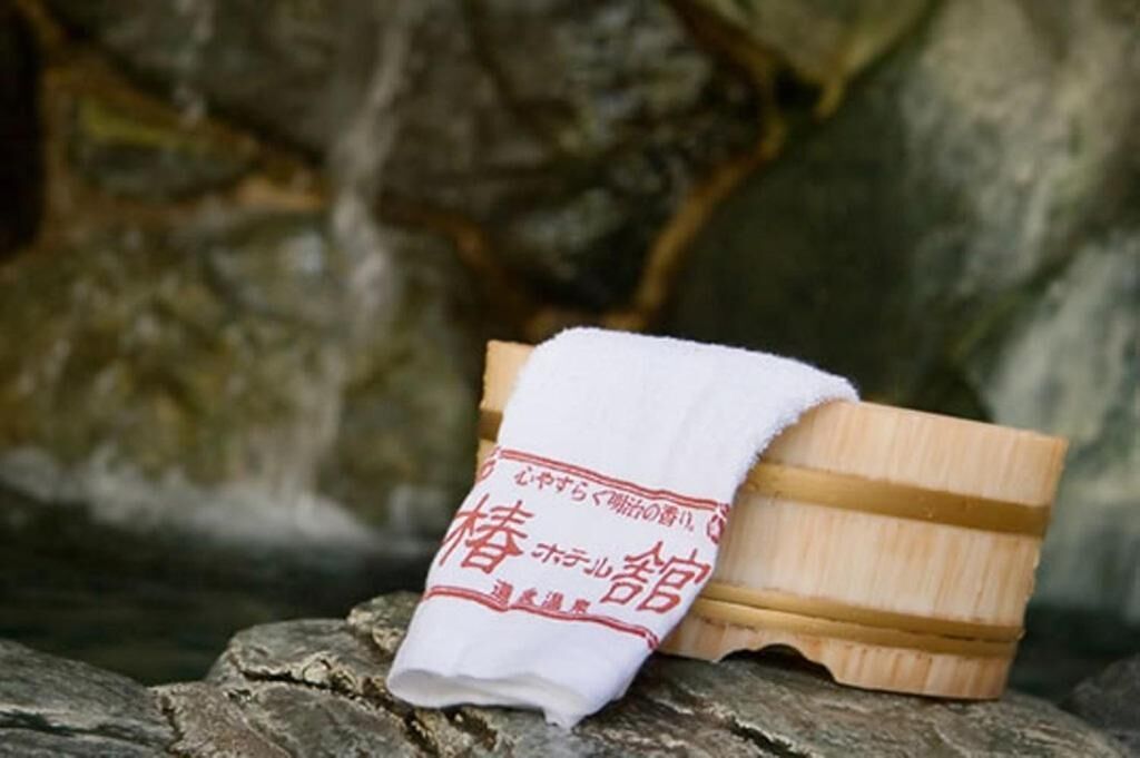 A wooden bath with a white towel on top, placed on a stone surface.