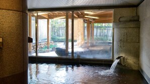A traditional Japanese onsen with a stone bath, wooden beams, and a view of a natural landscape. - Dogo Onsen Hotel Tsubakikan (Matsuyama)